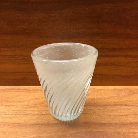 Vaso Murano artesanal cor gelo com detalhes em pó de ouro, peça de decoração sofisticada sobre fundo claro.
